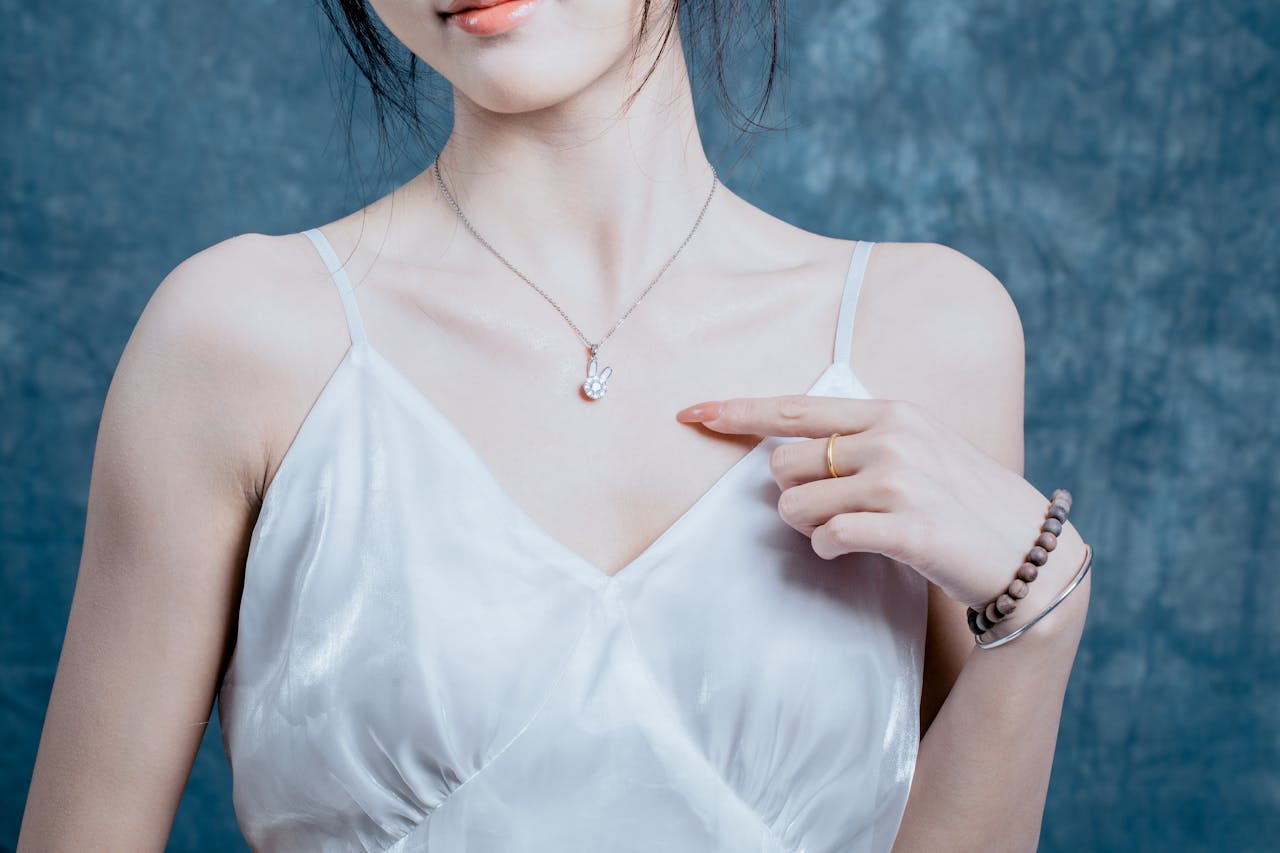 Close-up of an Asian woman in a white dress showcasing elegant necklace and bracelets.